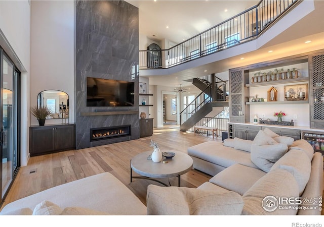 living room with a fireplace, light hardwood / wood-style floors, a high ceiling, and plenty of natural light