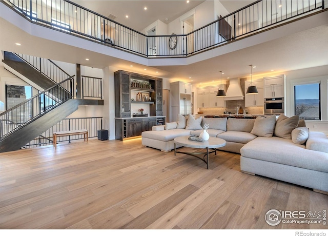 living room featuring a towering ceiling, bar, and light hardwood / wood-style flooring