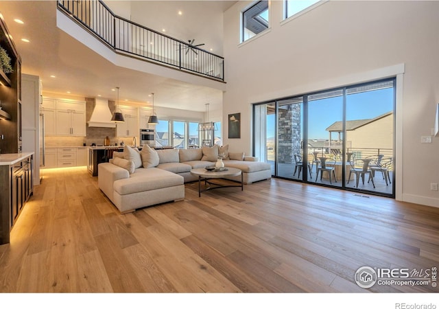 living room featuring light wood-type flooring, a wealth of natural light, and a high ceiling