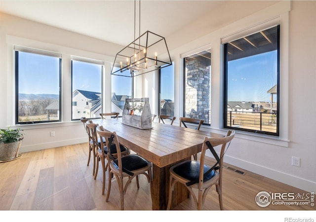 dining area with wood-type flooring, a mountain view, and an inviting chandelier