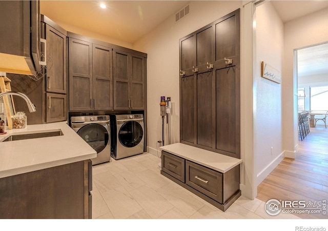 washroom featuring washer and dryer, cabinets, and sink