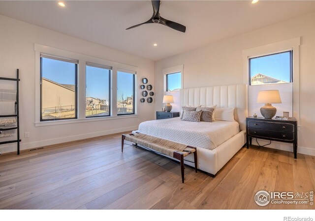 bedroom featuring light wood-type flooring, multiple windows, and ceiling fan