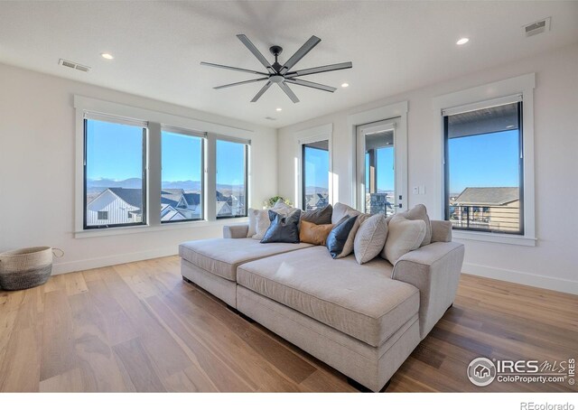 living room featuring a mountain view, hardwood / wood-style floors, and ceiling fan