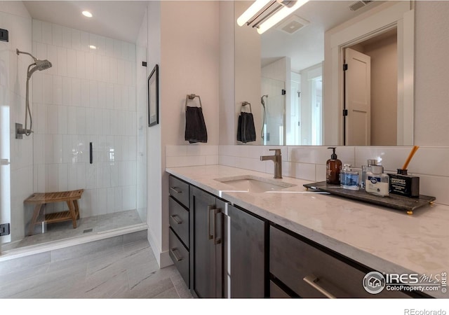 bathroom with backsplash, tiled shower, and vanity