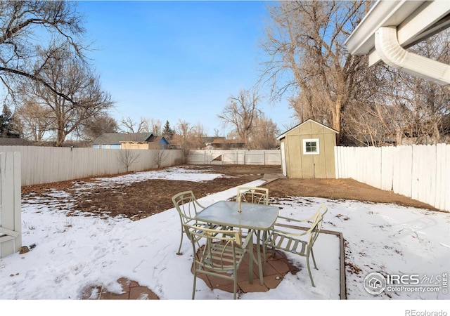 yard layered in snow featuring a storage shed