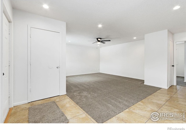 empty room with ceiling fan, a textured ceiling, and light tile patterned floors