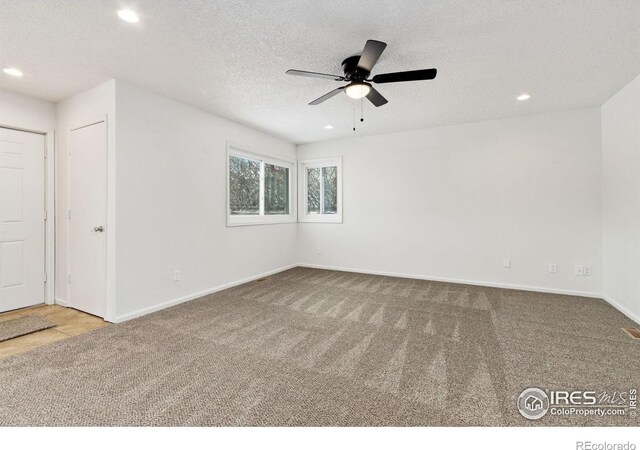 carpeted spare room featuring a textured ceiling and ceiling fan