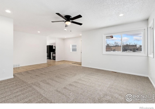 unfurnished living room featuring ceiling fan, light colored carpet, and a textured ceiling