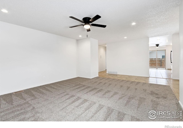 spare room featuring ceiling fan, light colored carpet, and a textured ceiling