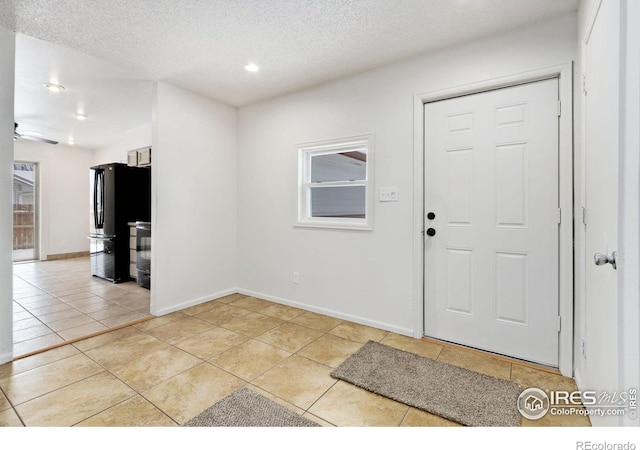 foyer with light tile patterned flooring, a textured ceiling, and ceiling fan