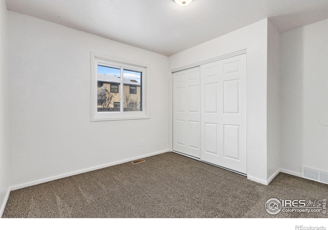 unfurnished bedroom with a closet and dark colored carpet