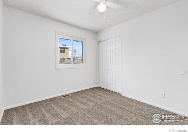 carpeted spare room with a textured ceiling and ceiling fan