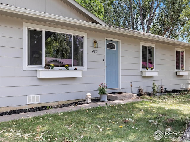 doorway to property with a lawn