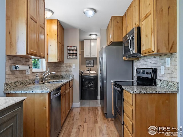 kitchen featuring sink, washer / clothes dryer, light stone countertops, and appliances with stainless steel finishes