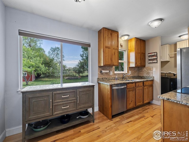 kitchen featuring sink, light hardwood / wood-style flooring, appliances with stainless steel finishes, and tasteful backsplash