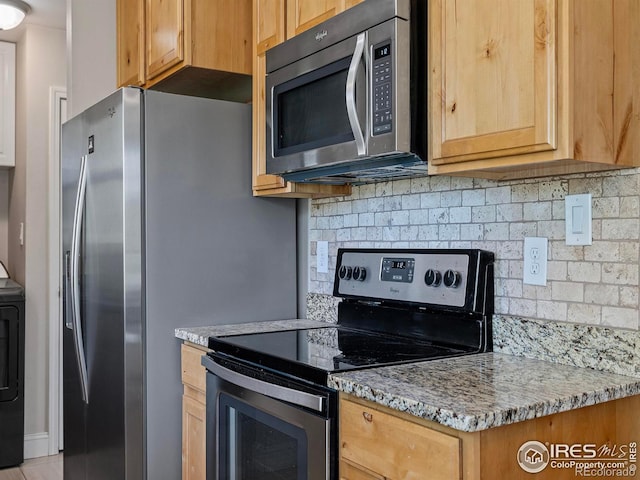 kitchen with tasteful backsplash, washer / dryer, light stone countertops, and appliances with stainless steel finishes