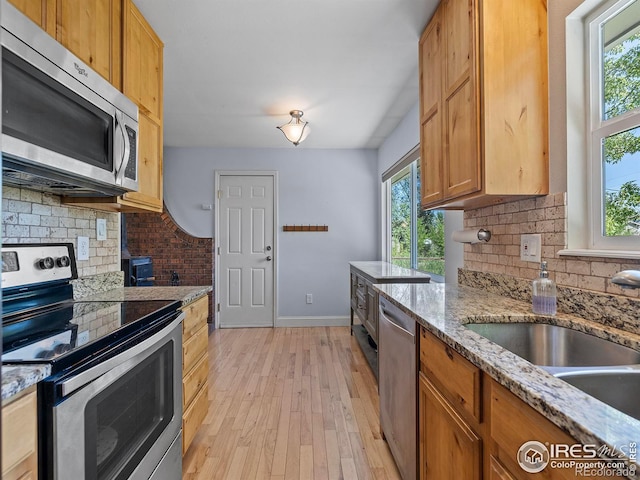 kitchen with sink, backsplash, light stone countertops, and appliances with stainless steel finishes