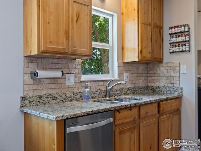 kitchen with sink, stainless steel dishwasher, decorative backsplash, and light stone counters