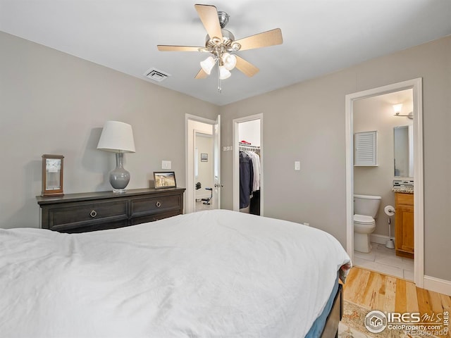 bedroom with ceiling fan, ensuite bathroom, a spacious closet, light hardwood / wood-style floors, and a closet