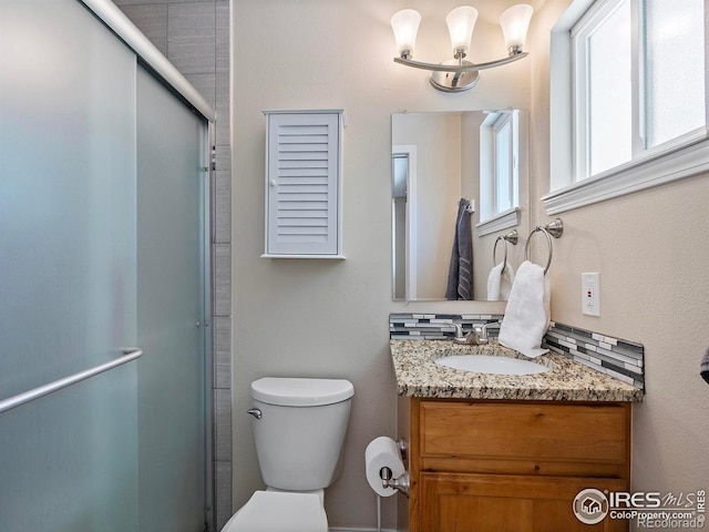 bathroom with backsplash, toilet, a shower with shower door, and vanity