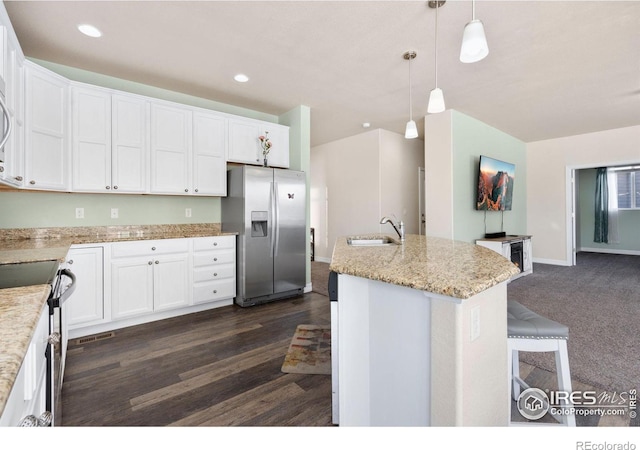 kitchen featuring appliances with stainless steel finishes, white cabinets, an island with sink, sink, and hanging light fixtures