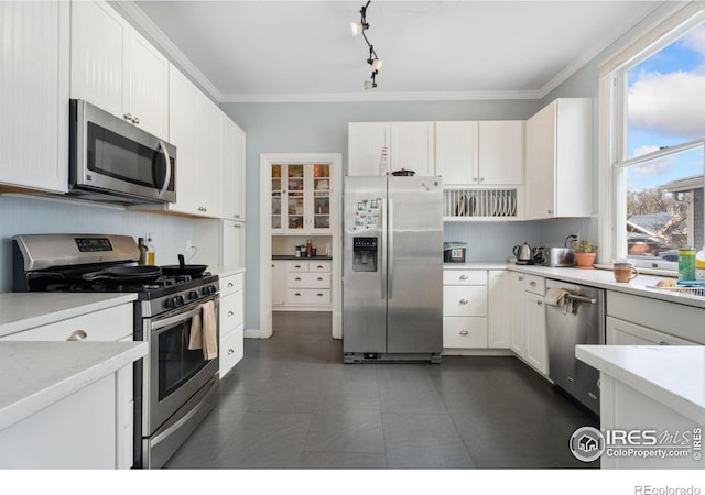 kitchen with white cabinetry, ornamental molding, and stainless steel appliances