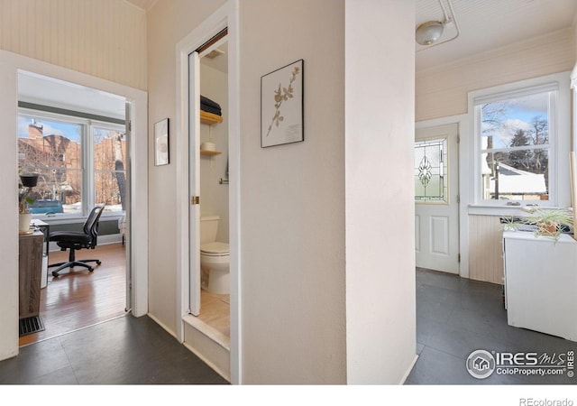 hallway featuring a wealth of natural light and dark tile patterned floors