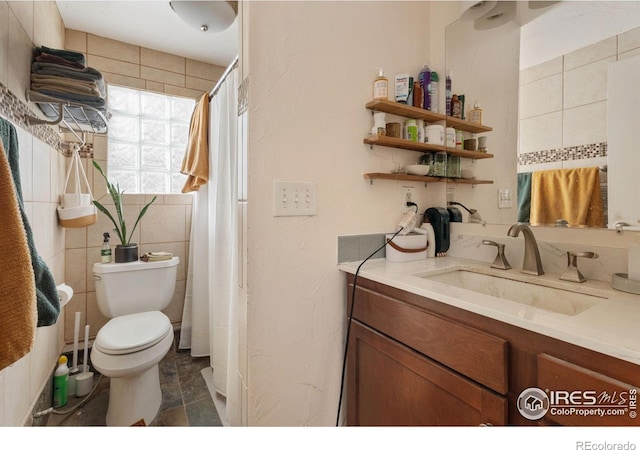 bathroom featuring toilet, tile walls, and vanity