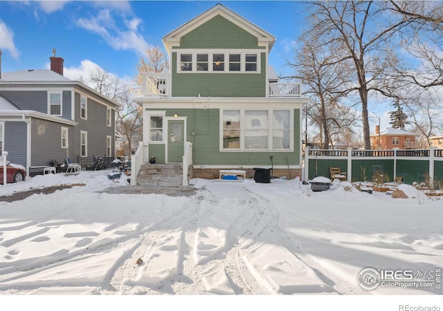 snow covered rear of property featuring a balcony