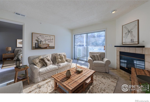 tiled living room with a tile fireplace and a textured ceiling