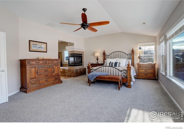 carpeted bedroom featuring ceiling fan, a tile fireplace, and vaulted ceiling