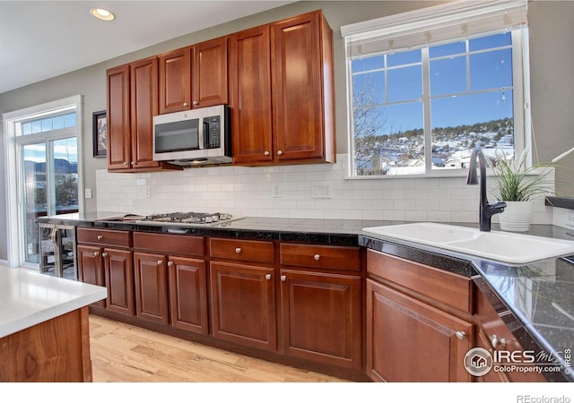 kitchen featuring sink, stainless steel appliances, light hardwood / wood-style flooring, and tasteful backsplash