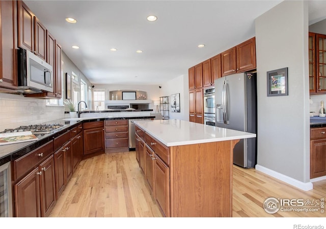 kitchen with appliances with stainless steel finishes, light wood-type flooring, tasteful backsplash, a kitchen island, and a breakfast bar area