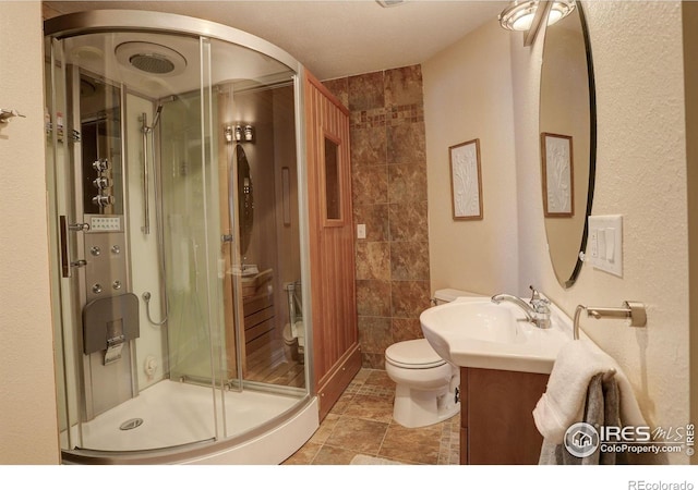 bathroom featuring toilet, a shower with shower door, and vanity