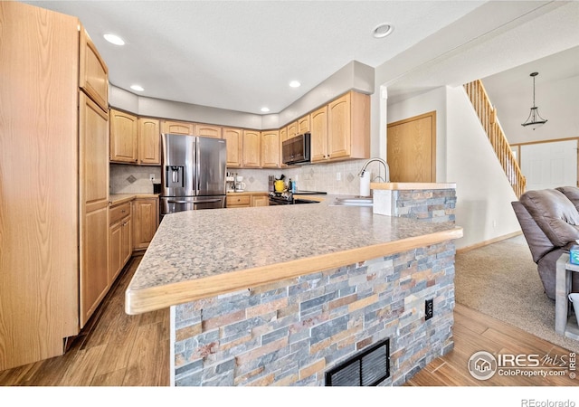 kitchen with stainless steel refrigerator with ice dispenser, light brown cabinets, sink, hanging light fixtures, and kitchen peninsula