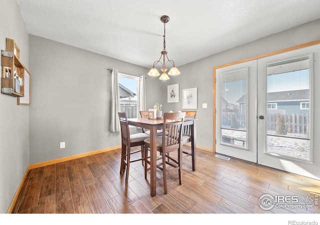 dining area featuring hardwood / wood-style flooring, a chandelier, and a healthy amount of sunlight