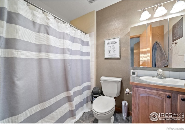 bathroom with vanity, toilet, and backsplash