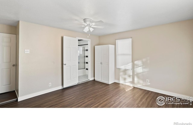 unfurnished bedroom featuring ceiling fan, connected bathroom, dark wood-type flooring, and a textured ceiling