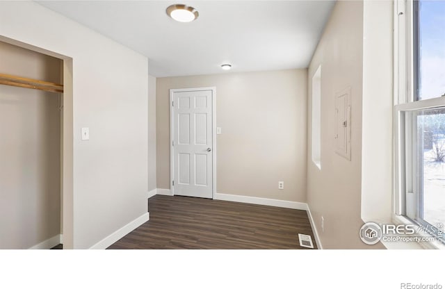 unfurnished bedroom featuring a closet, electric panel, and dark hardwood / wood-style floors