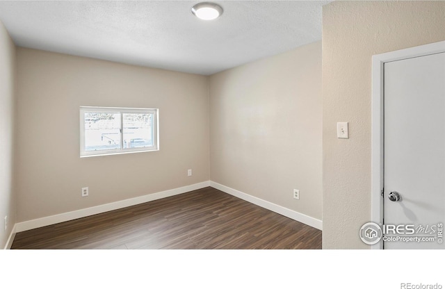 spare room featuring a textured ceiling and dark hardwood / wood-style floors