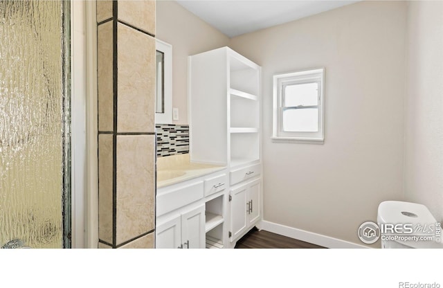 bathroom with hardwood / wood-style floors, a shower with door, tasteful backsplash, and vanity