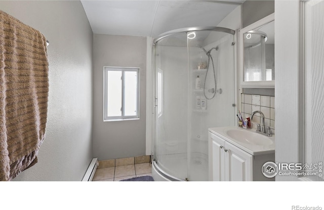 bathroom with tasteful backsplash, baseboard heating, tile patterned flooring, vanity, and a shower with door