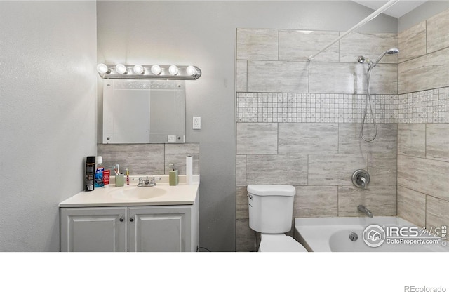 full bathroom featuring tiled shower / bath combo, toilet, tasteful backsplash, and vanity