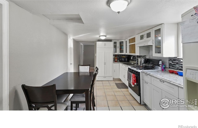 kitchen featuring white appliances, white cabinets, tasteful backsplash, light stone counters, and light tile patterned floors