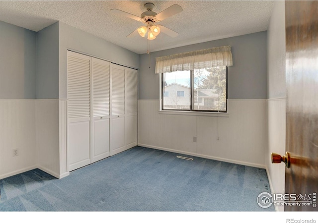 unfurnished bedroom with ceiling fan, a textured ceiling, a closet, and carpet floors