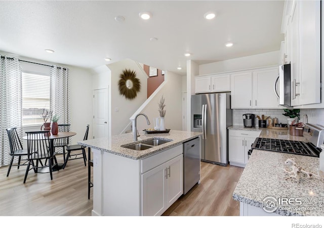 kitchen with sink, white cabinetry, appliances with stainless steel finishes, and a center island with sink