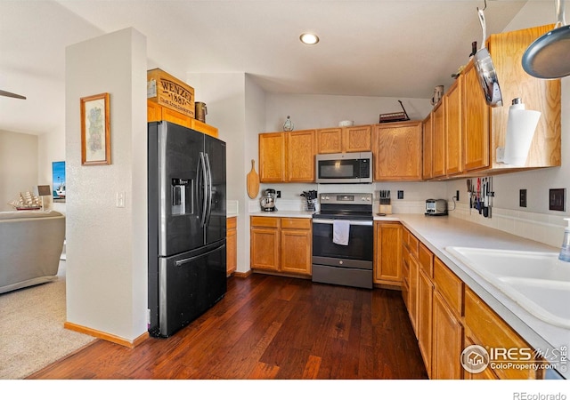 kitchen with dark wood-type flooring, sink, appliances with stainless steel finishes, and vaulted ceiling