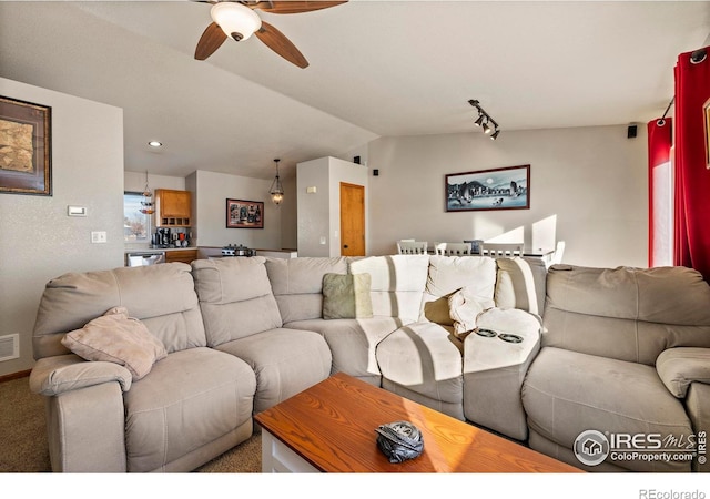 carpeted living room with rail lighting, vaulted ceiling, and ceiling fan