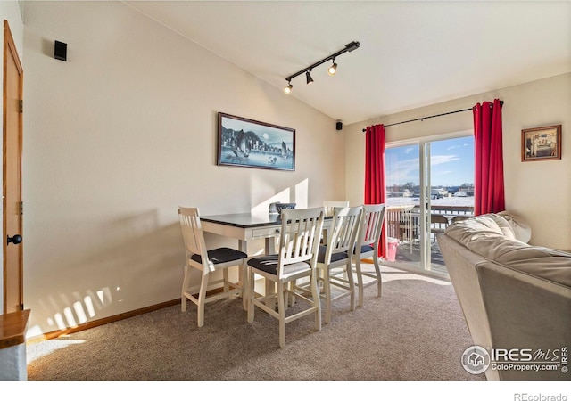 dining room with rail lighting, vaulted ceiling, and carpet