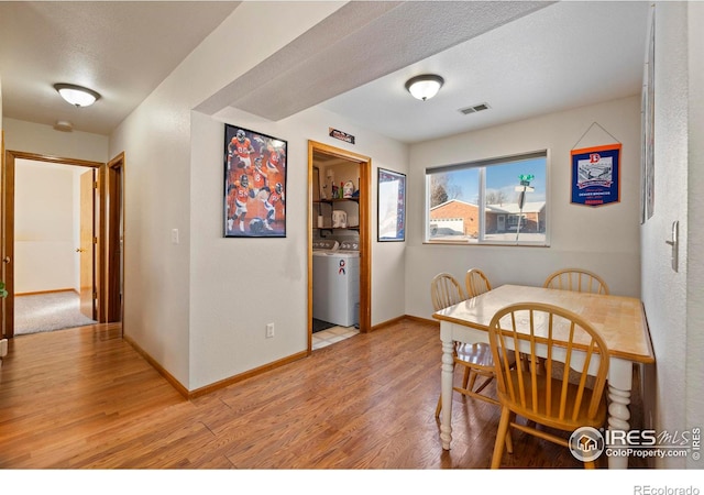 dining space with light hardwood / wood-style floors, a textured ceiling, and washer / dryer